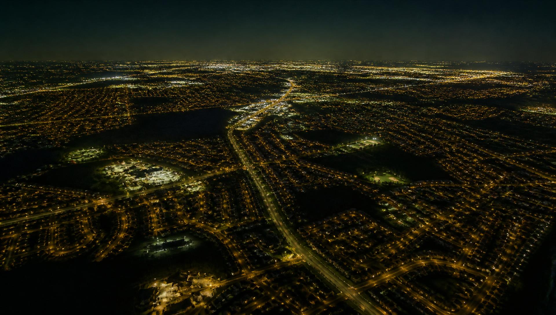 High-altitude night view of a lit suburban grid